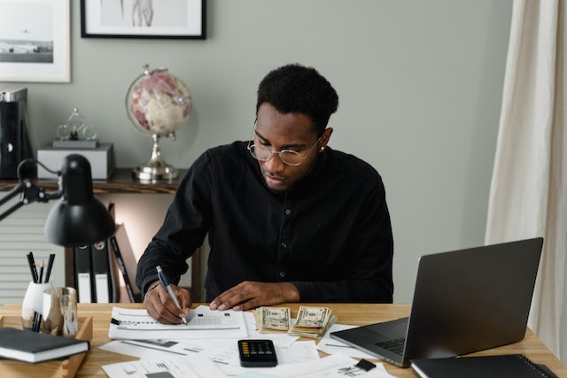 accountant looking over income reports with some stacks of money in their desk